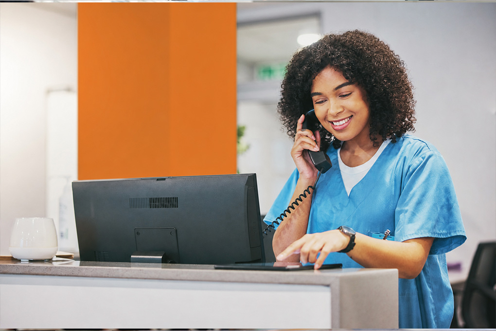 Executive Medical Office Assistant assisting patients at a medical reception desk